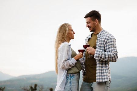 Smiling couple toasting wine glasses outdoors in mountainsの写真素材