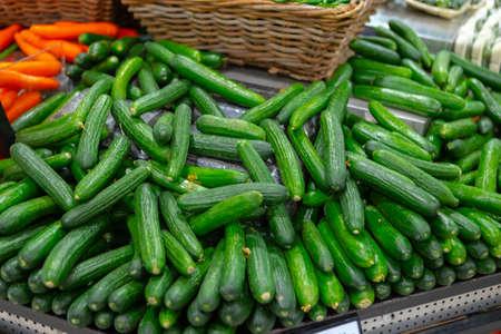 Pile of fresh cucumbers on counter in supermarketの写真素材