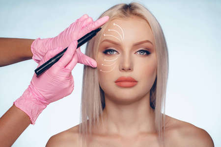 Beautiful blonde woman with markings for plastic surgery on her faceの写真素材