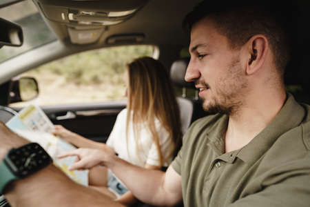 Young loving couple on a road trip using map inside a carの写真素材