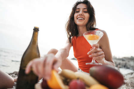 Portrait of young woman with cocktail glass chilling on a beachの写真素材