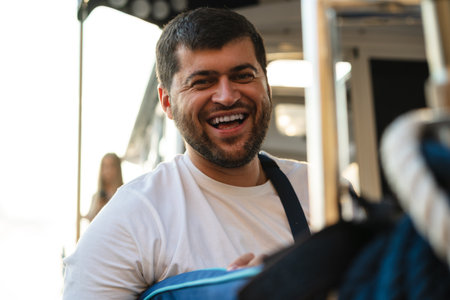 Portrait of a young caucasian bearded man sitting on a deck of sailboatの写真素材
