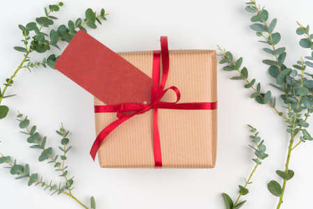Gift boxes packed in craft paper with simple decor of green plant branchesの写真素材