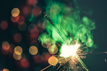 Close-up of green holiday sparkler in the dark