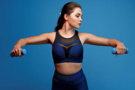 Portrait of a fitness model working out with dumbbells on grey backgroundの写真素材