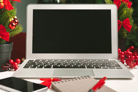 Open notepad and computer on table with christmas decorの写真素材