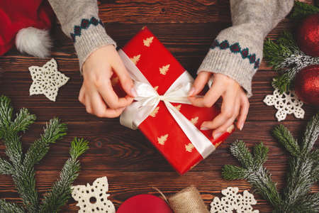 Top view of a woman hands with a Christmas gift on wooden backgroundの写真素材