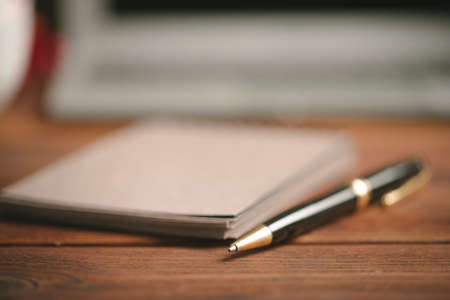 Close up of an open notepad with pen on wooden table