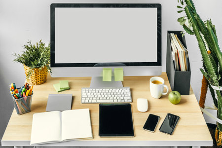 Computer monitor with mockup white screen on office table with suppliesの写真素材