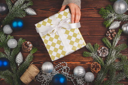 Christmas decorations on wooden table with decorated gift in womans handsの写真素材