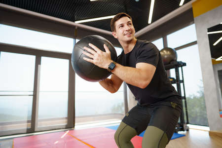 Fit young man exercising with fitness ball in a gym