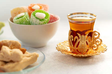 Assortment of Turkish delights with glass of tea on gray background