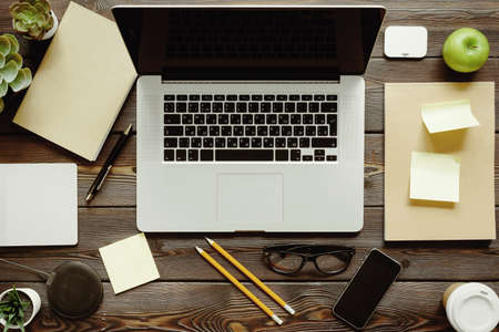 Office desk with laptop computer, supplies and green apple, top viewの写真素材