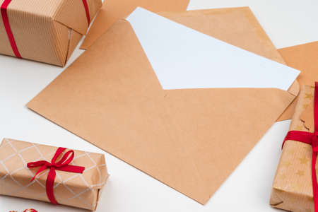 Christmas gift with red bow and greeting card on white wooden backgroundの写真素材