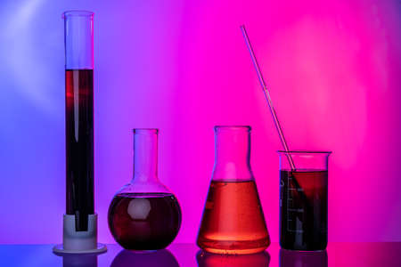 Laboratory glass tubes with chemicals on bright pink background