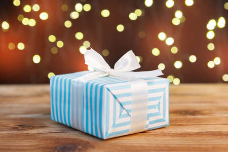Festive gift box on wooden table against brown bokeh backgroundの写真素材