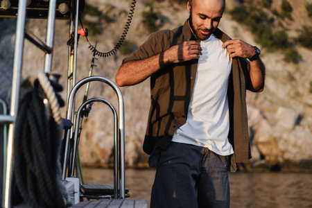 Young african american man relaxing on a sailboat in open sea at sunset