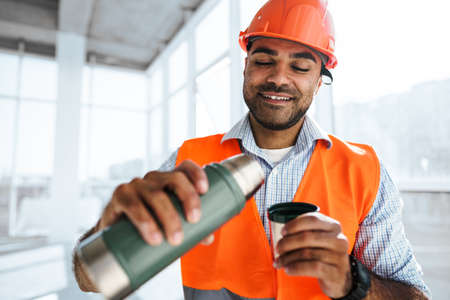 Portrait of a man worker in workwear on a break drink coffee and have restの写真素材