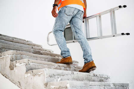Professional builder carrying metal ladder, close upの写真素材