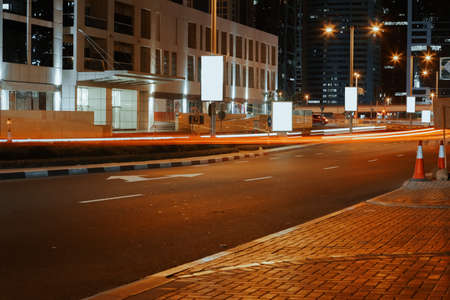 Empty asphalt road with modern buildings at night in Dubai