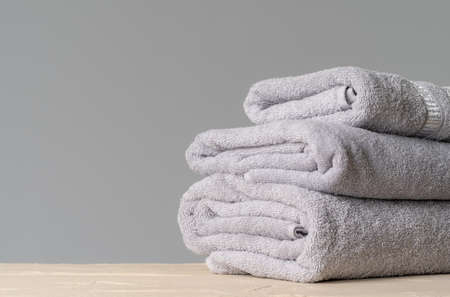 Pile of clean new towels against grey wallの写真素材