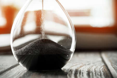 Closed up of sandglass or hourglass on background of bookの写真素材