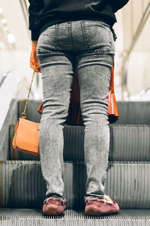 Legs standing on the escalator of a shopping mallの写真素材