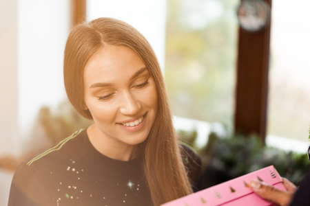 Surprised young woman opens a pink box with a present .の写真素材