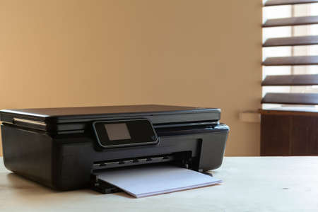 Front view of a black printer machine on a tableの写真素材