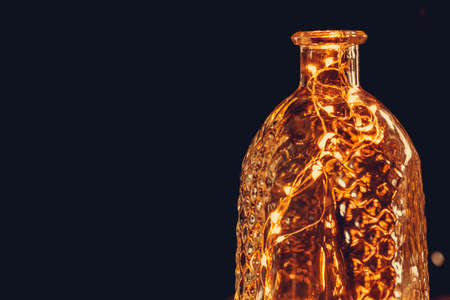 Christmas lights garland put in bottle in the dark close upの写真素材
