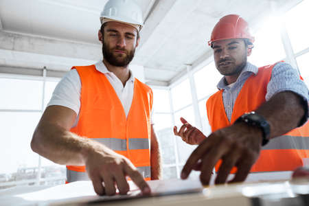 Two engineers man looking at project plan on the table in construction siteの写真素材