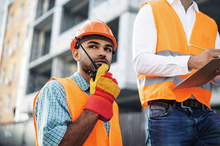 Young construction worker in uniform using walkie talkie on siteの写真素材