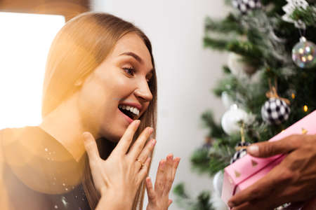 Surprised young woman opens a pink box with a present .の写真素材