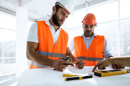 Two engineers man looking at project plan on the table in construction site