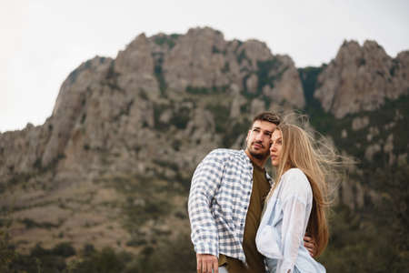 Happy loving couple hiking and hugging in mountains
