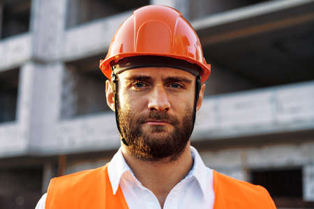 Builder wearing hardhat and safety vest standing on a commercial construction siteの写真素材