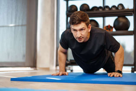Young athletic man doing push-ups in a gym, close upの写真素材