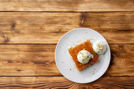 Turkish dessert kunefe served with ice cream on wooden backgroundの写真素材