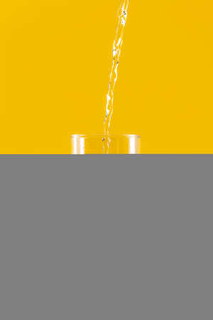 Cold water pouring from a bottle into a glassの写真素材