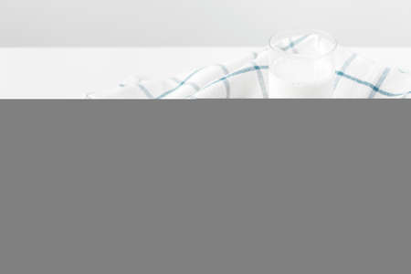 Milk glass and biscuit cookies with kitchen cloth on light backgroundの写真素材