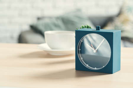 Old-fashioned alarm clock and house plant on wooden tableの写真素材