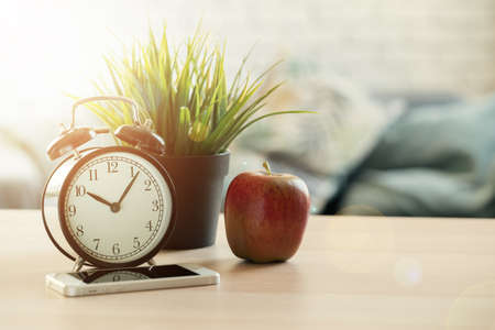 Its time for school. Vintage alarm clock and apple on wooden deskの写真素材