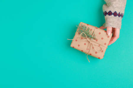Woman hands holding gift box on green background