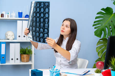 Woman doctor examining patients MR image in her office