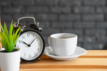 Classic vintage alarm clock and coffee cup on wooden backgroundの写真素材