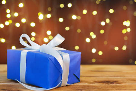 Christmas gift box on wooden table against brown bokeh backgroundの写真素材