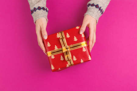 Gift box in female hands on pink backgroundの写真素材