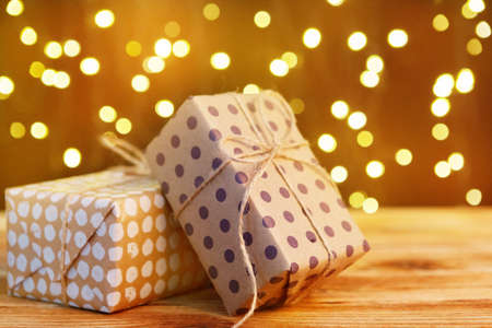 Festive gift box on wooden table against brown bokeh backgroundの写真素材