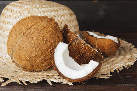Cracked coconut pieces on dark wooden background