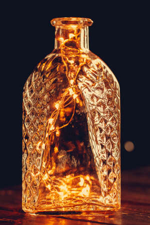 Christmas lights garland put in bottle in the dark close upの写真素材